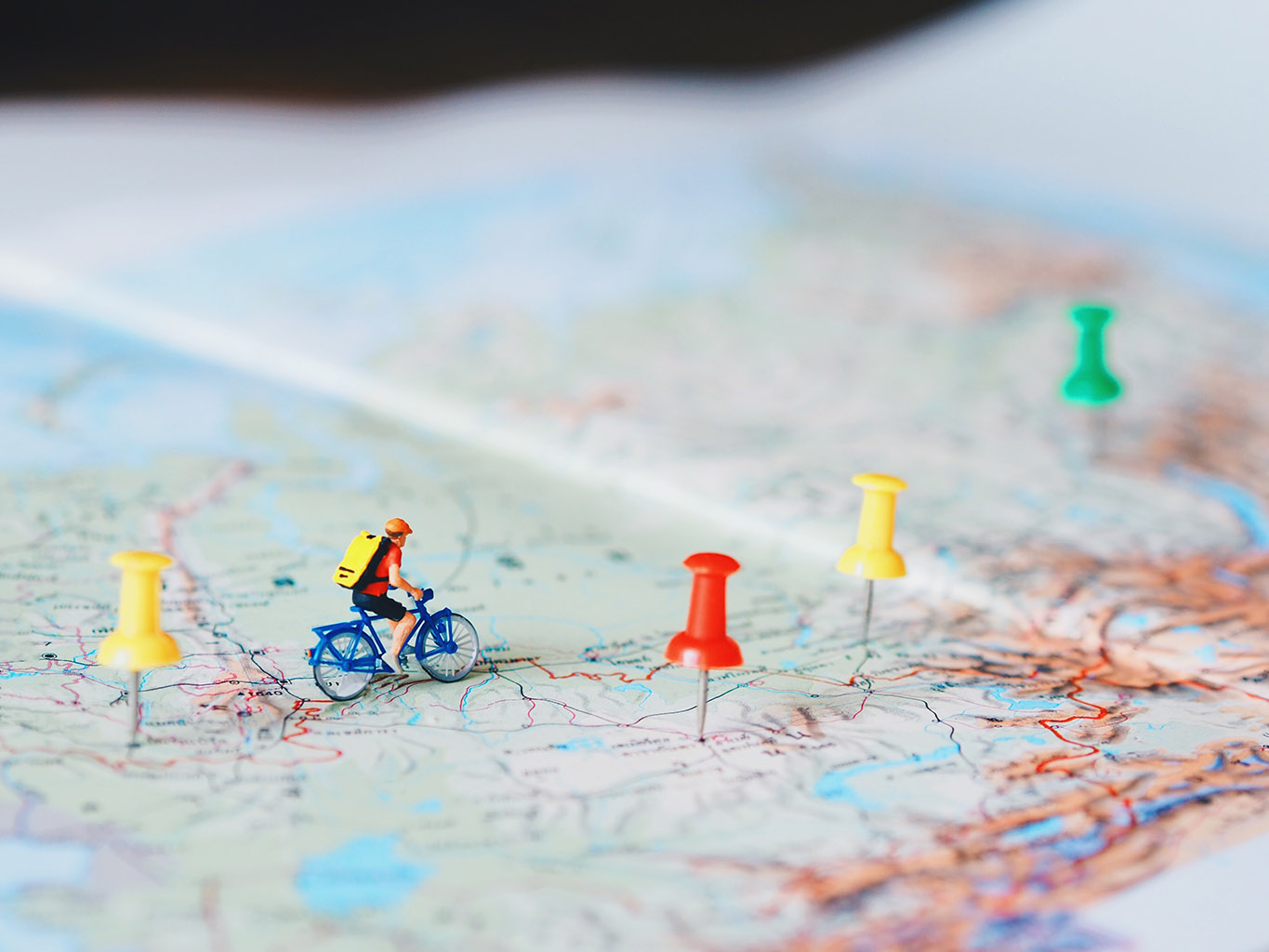 picture of a plastic cyclist on a paper map dotted with push-pins